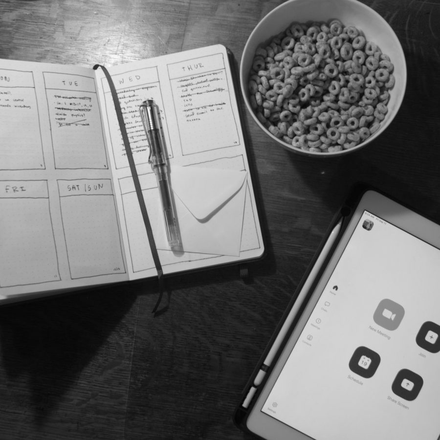 A paper planner with a bowl of Cheerios with an iPad with zoom open