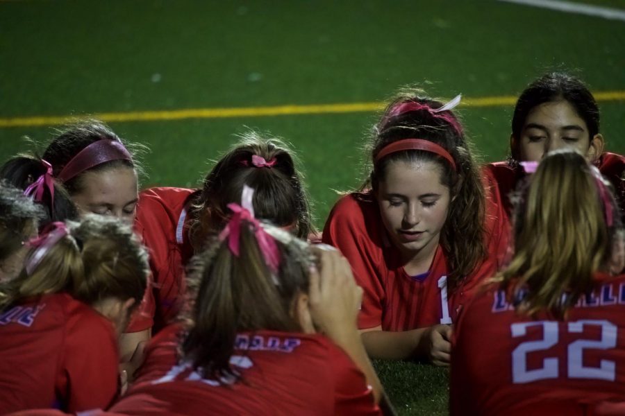 The girls soccer team prayed together on the field before the game started. 
