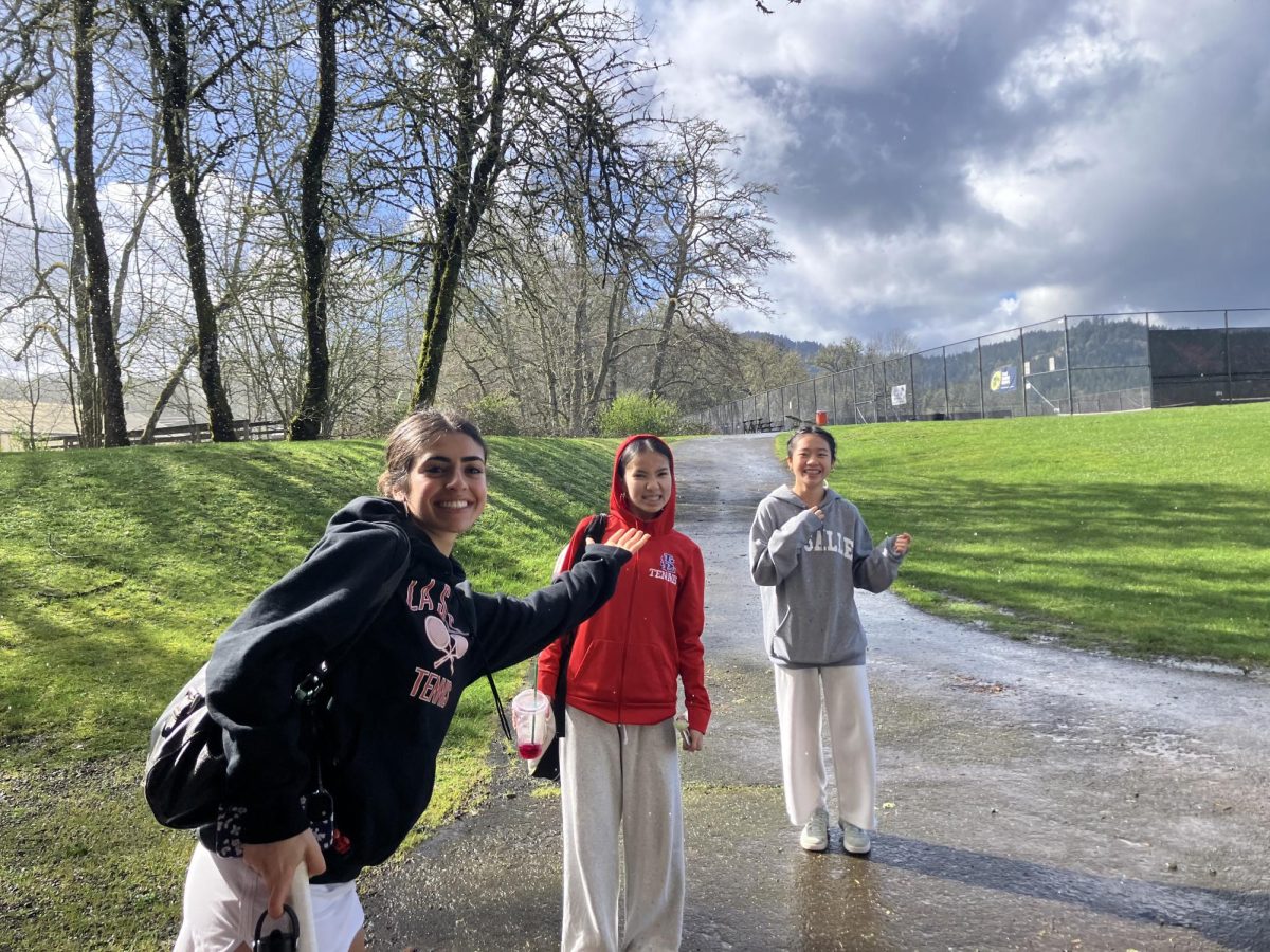 Girls tennis members smile in the rain after their match was cancelled on Monday, March 17.