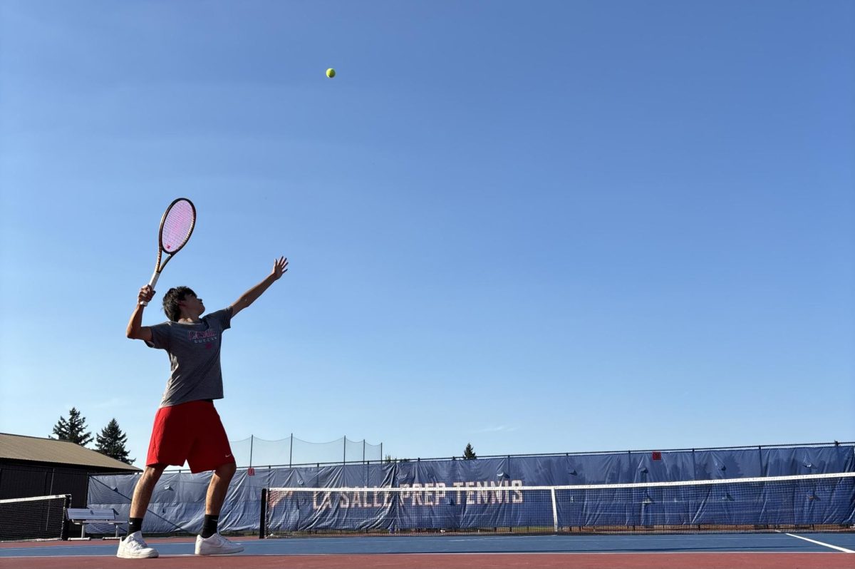 Students practice tennis on the La Salle tennis courts, enjoying a bright, sunny afternoon outside.